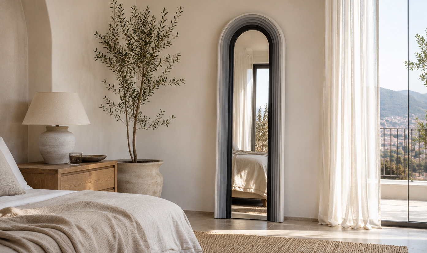 Round gold-framed wall mirror above a light sofa, against dark slatted panels with green plants.